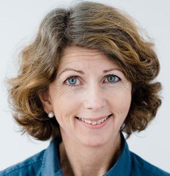 Smilende kvinne med halvlangt brunt h&aring;r og bl&aring; skjorte