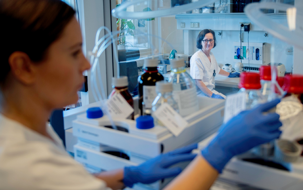 Two people in laboratory equipment work in a modern laboratory.