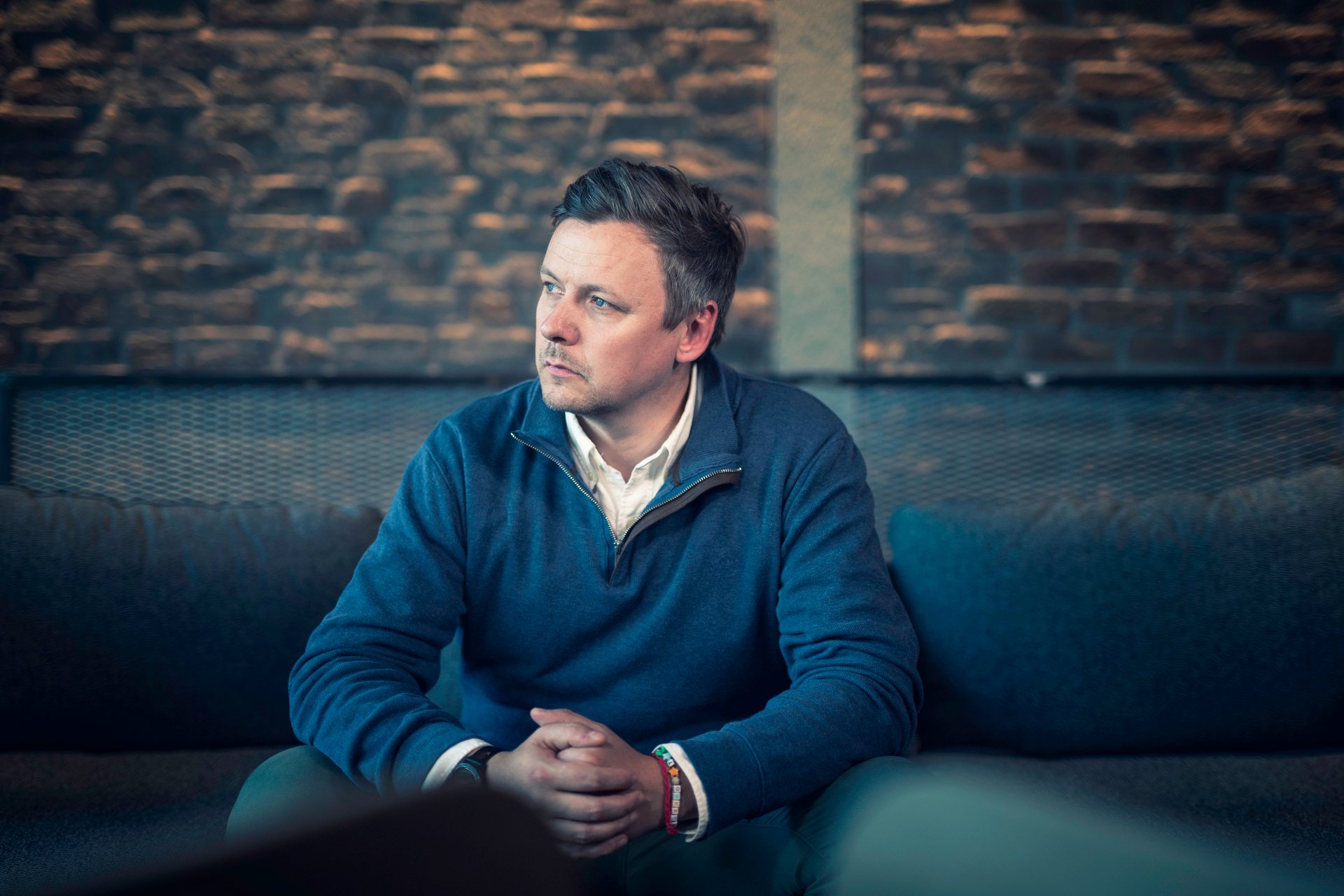 A man sits and reflects, symbolizing uncertainty and thoughts about downsizing and the future of work.