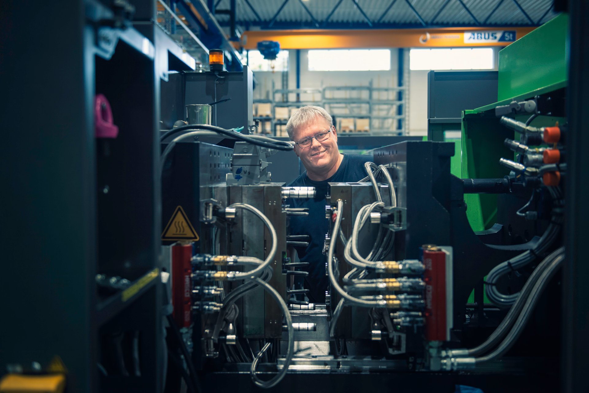 Male engineer with glasses sticks his head out between industrial equipment, NITO members who may be relevant for AFP illustrate.