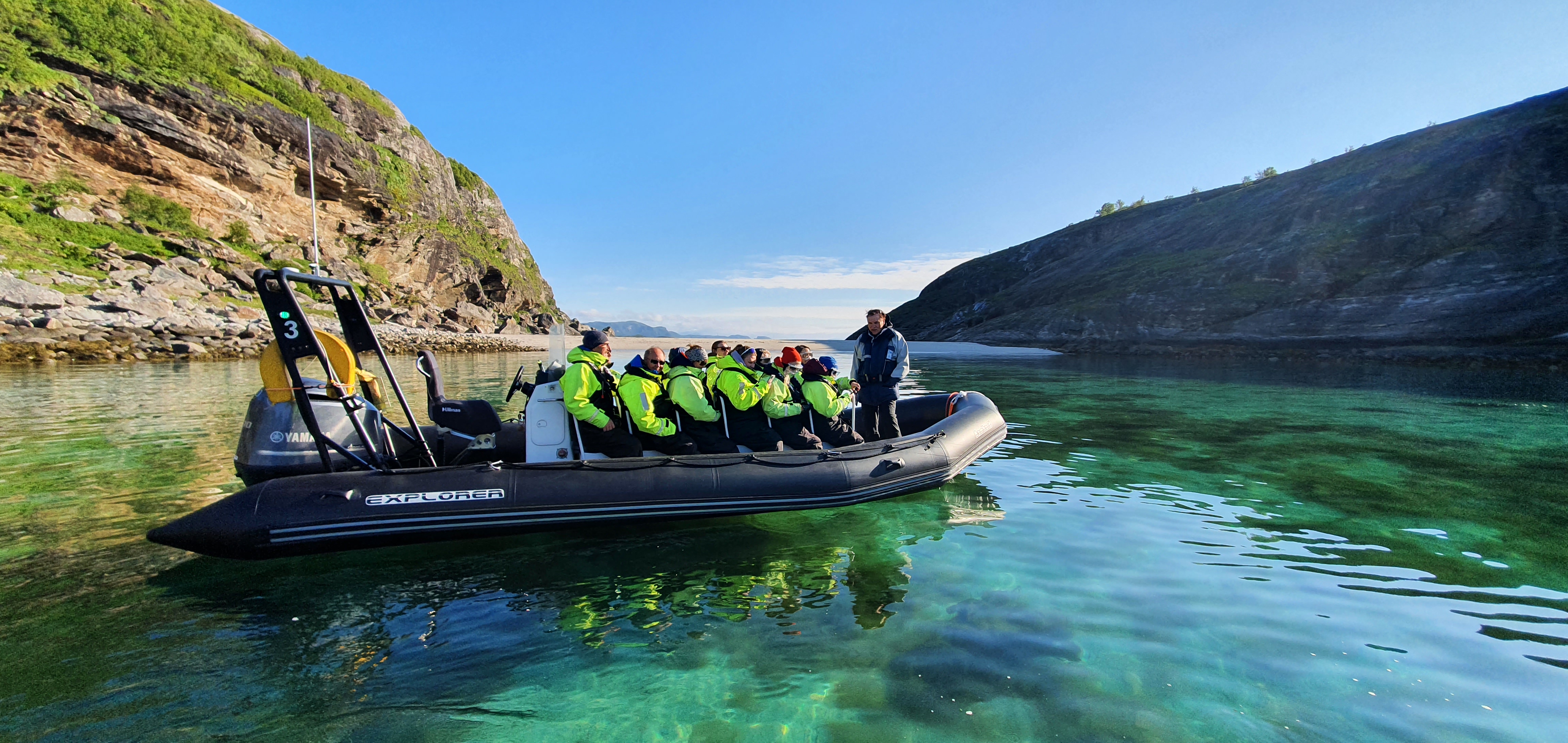 En rib på havet med berg og strand i bakgrunnen