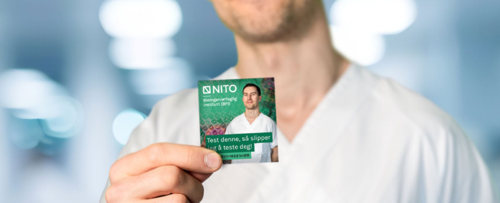 A man in a white coat smiles and holds up a green condom package with the text "Try this, so you don't have to get tested!"