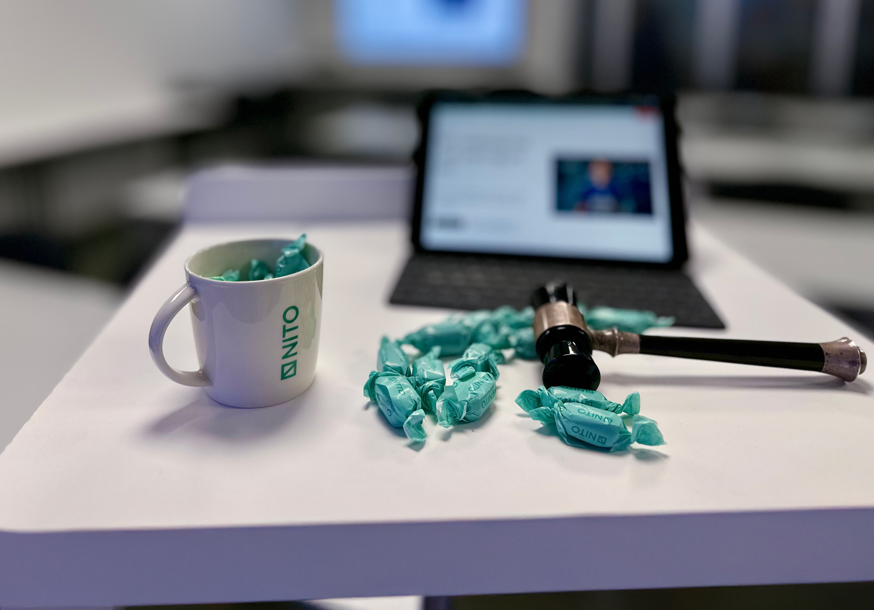 NITO kaffekopp, karameller og årsmøteklubbe. Pc i bakgrunnen.