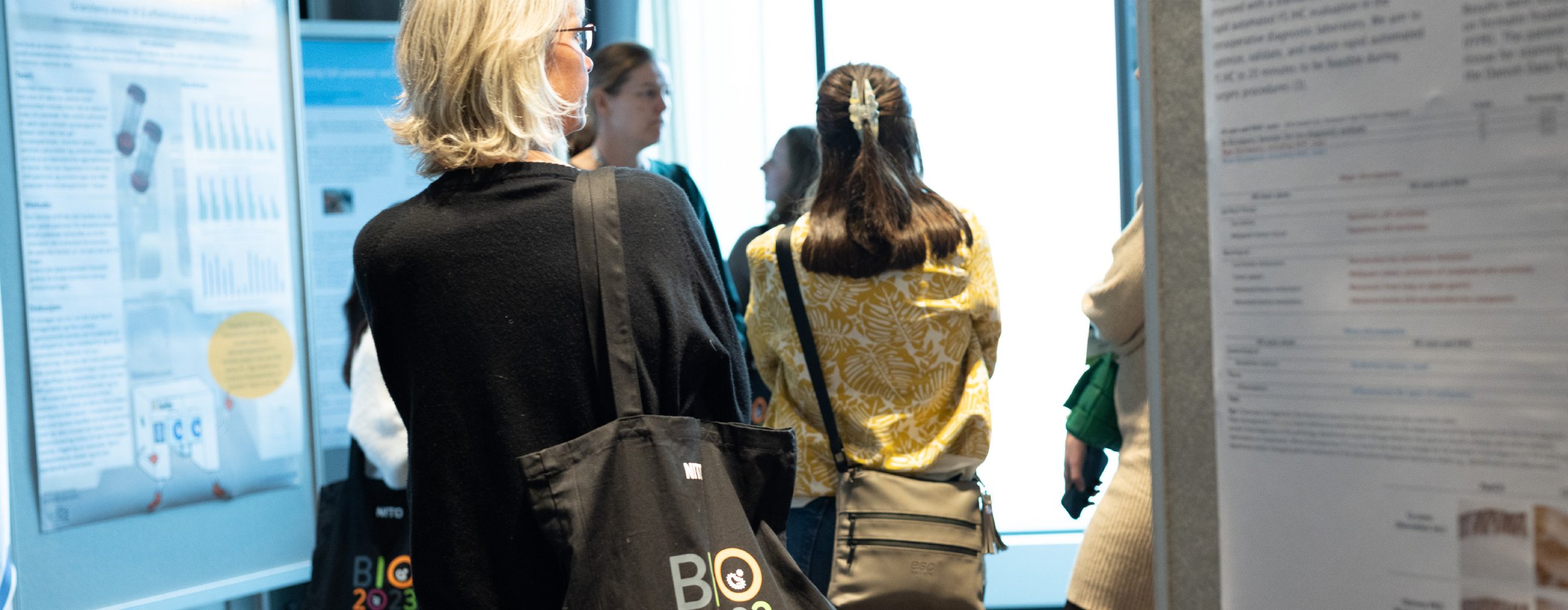 Several people stand together in front of posters with professional content at a conference exhibition.