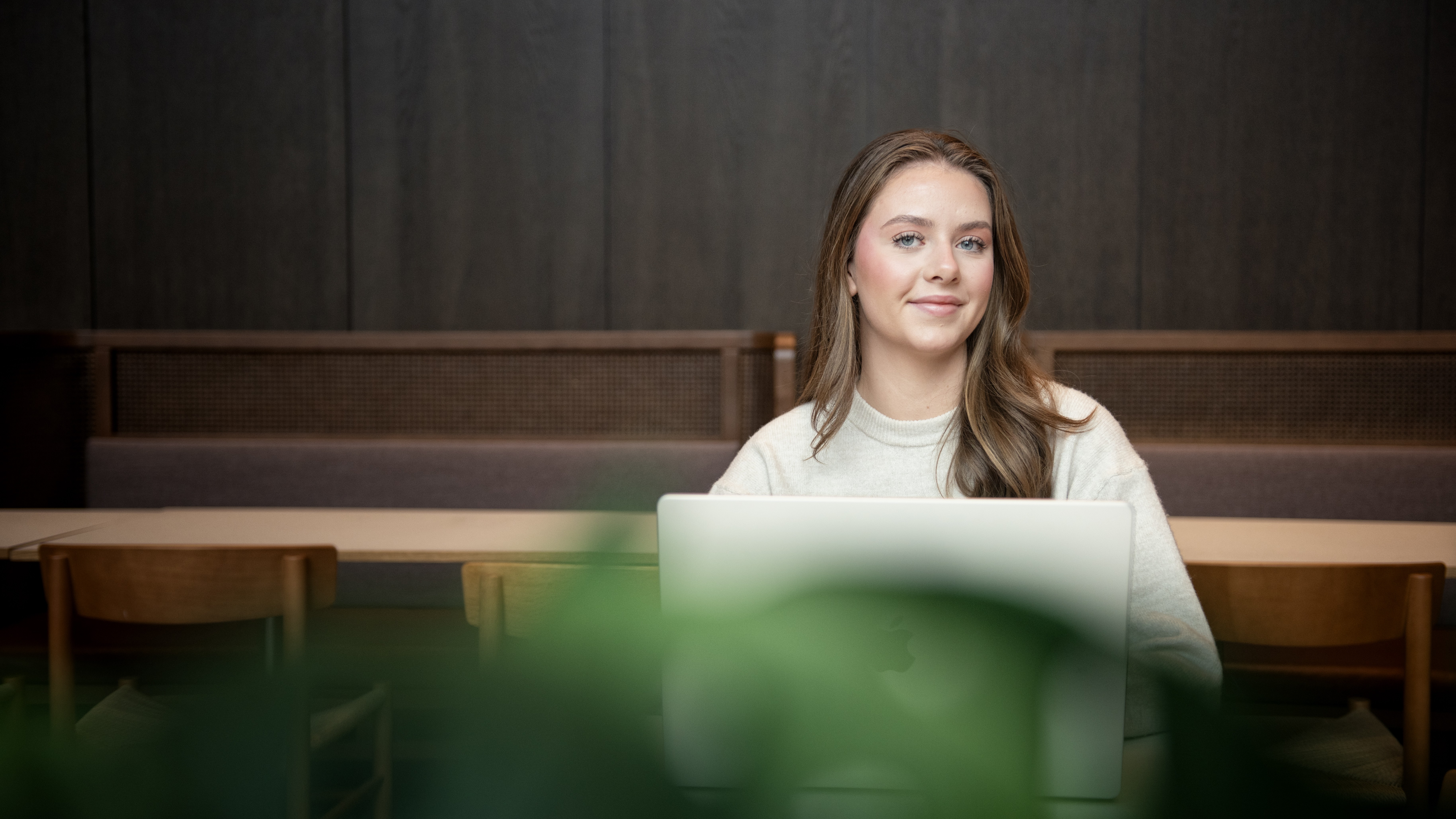 Jente som arbeider på pc, smiler til kamera 