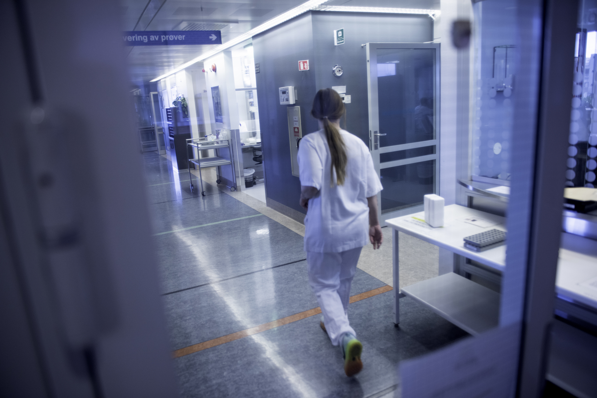 Ansatt i hvit arbeidsuniform går i en korridor på et sykehus