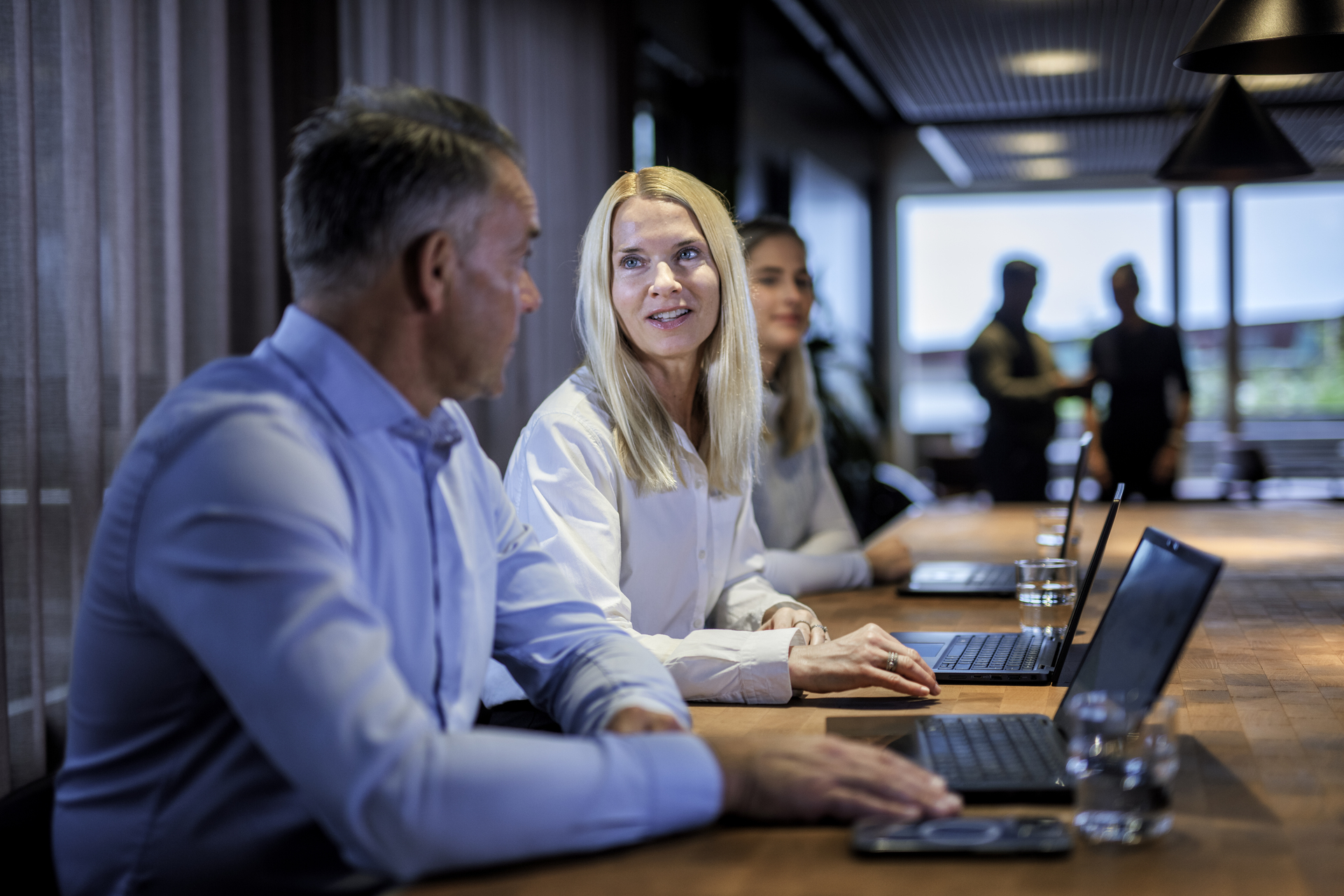 Employees in a meeting room who discuss and collaborate, with a focus on dialogue and co-determination in working life.