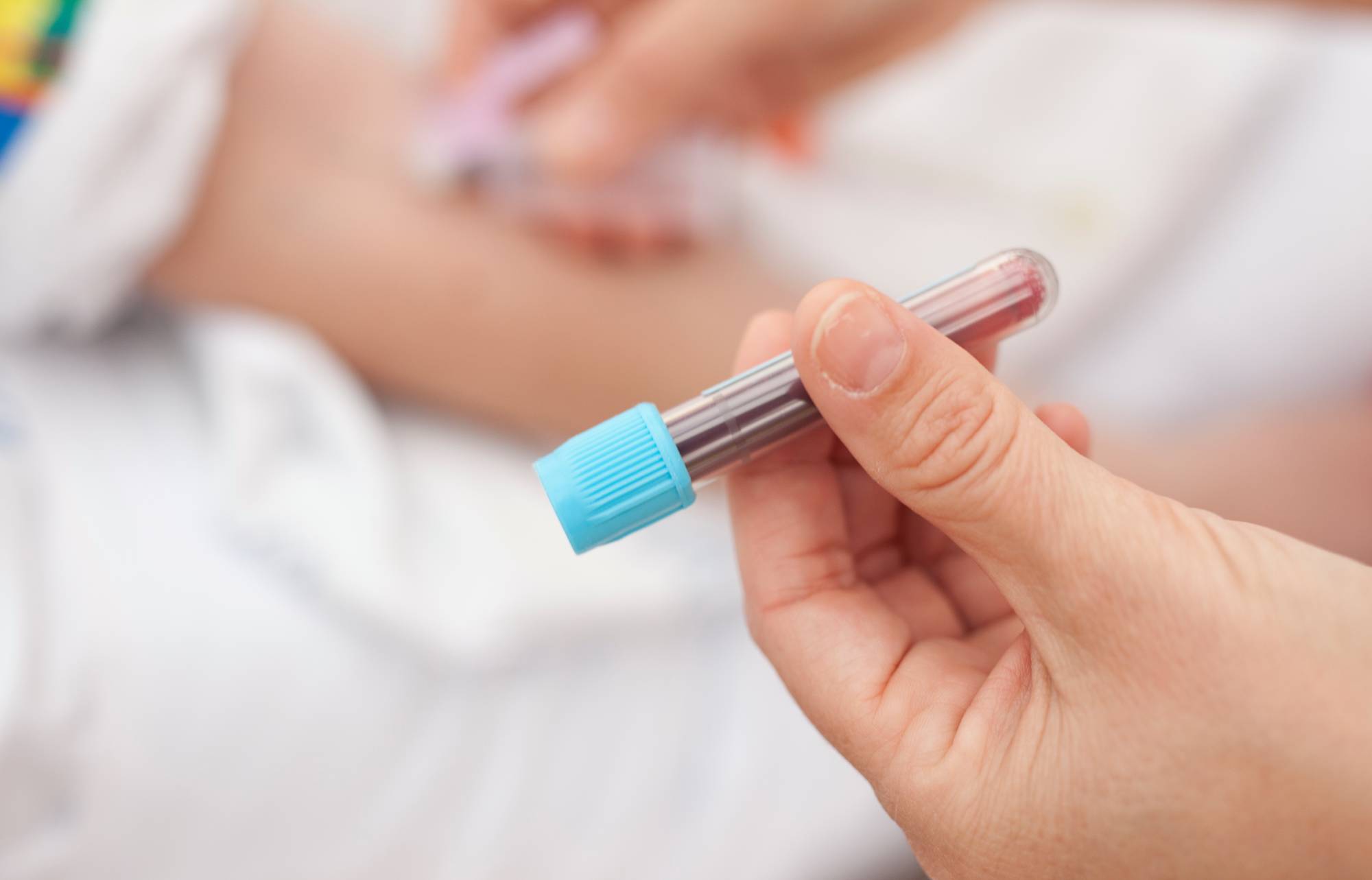 Image of a hand holding a blood test tube filled with blood.