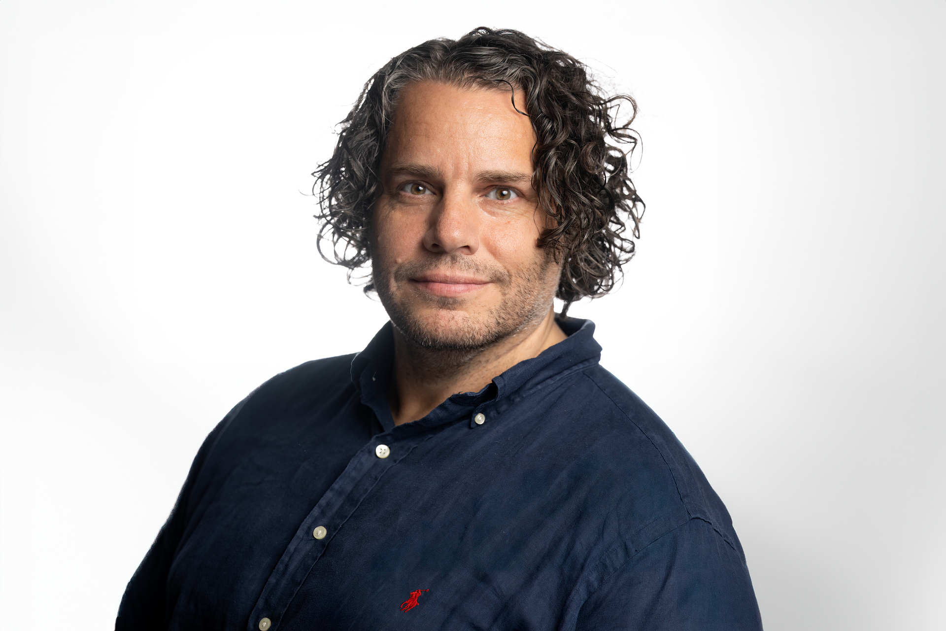 Bilde av mann med halvlangt krøllete hår og blå skjorte.