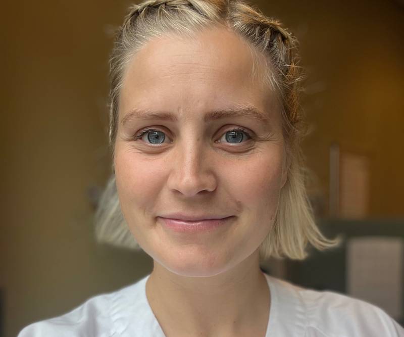 Smilende bioingeni&oslash;r med lyst h&aring;r og hvit helsefrakk 