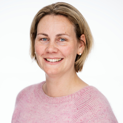 Woman with short blonde hair, wearing a pink sweater, against a light background.