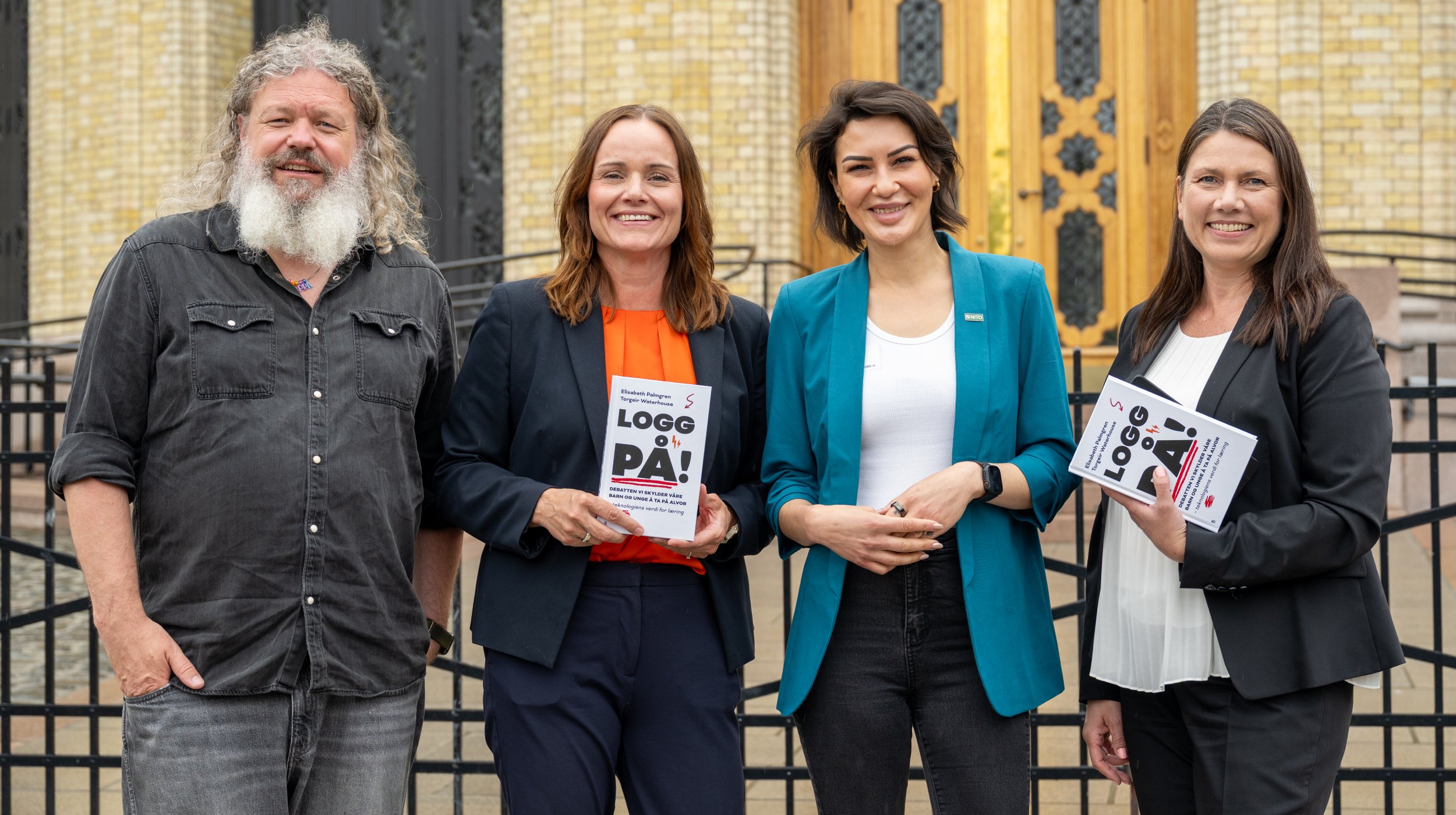 Four people standing in front of the Storting. They show off a book titled "Log in".