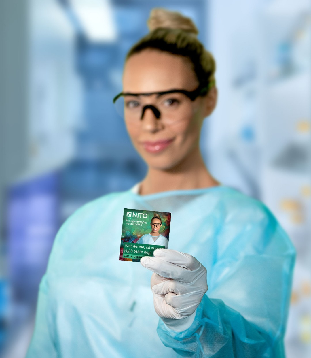 Kvinnelig bioingeni&oslash;r if&oslash;rt verneutstyr som holder opp en kondompakke