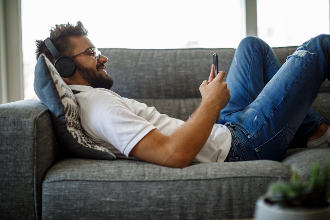 Man lying on couch with headset and mobile phone
