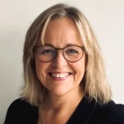 Portrait of smiling woman with glasses and semi-long blond hair.