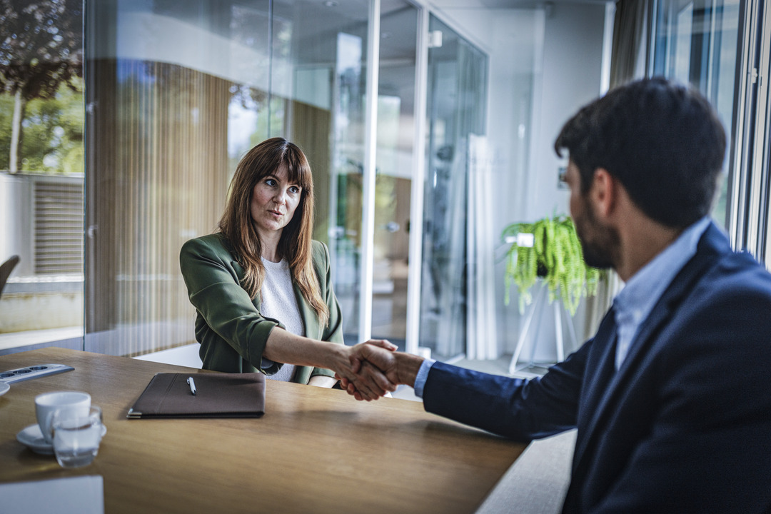 Ung kvinne og ung mann tar hverandre i hendene over bordet og blir enige om en avtale