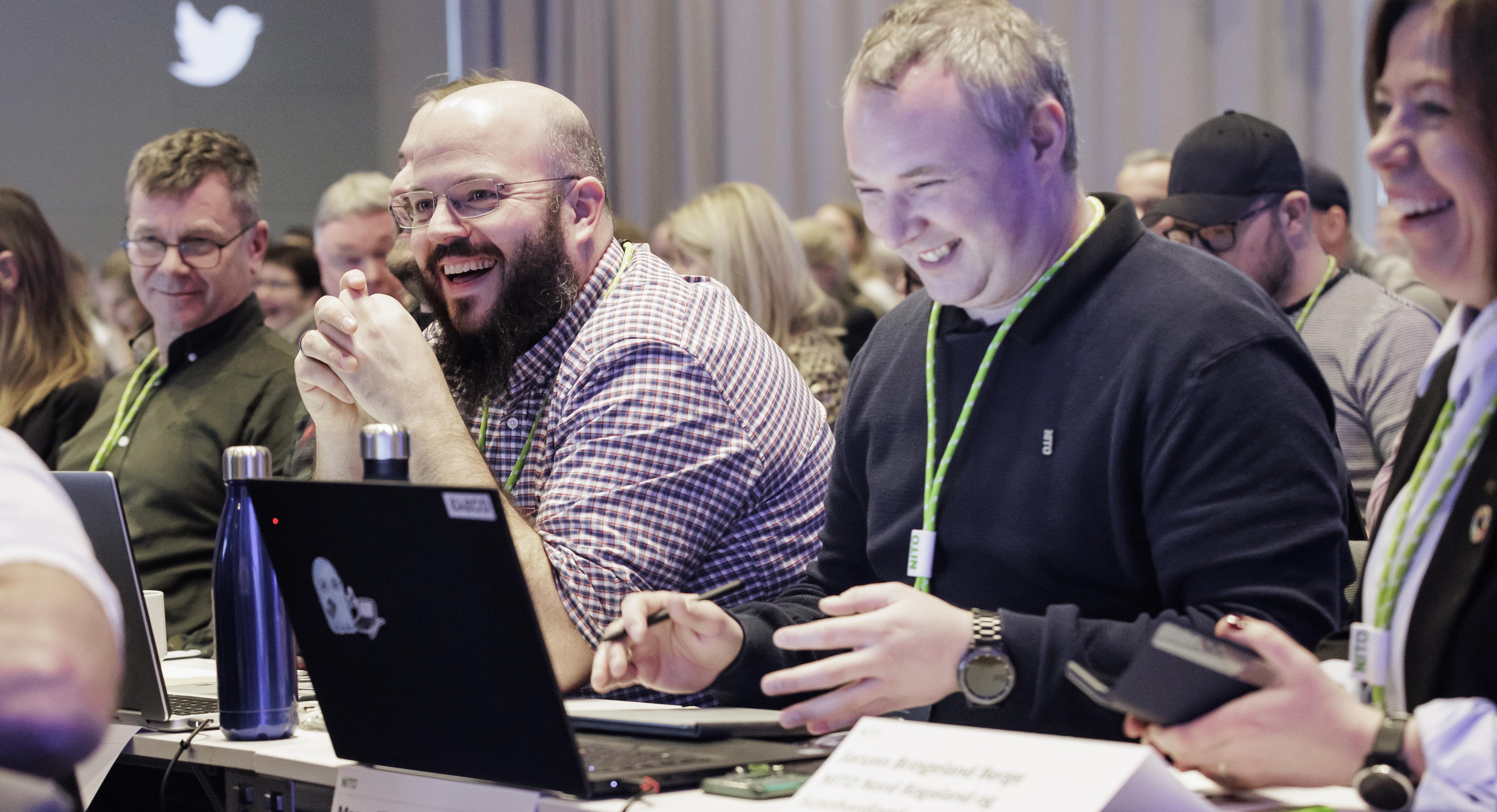 A group of smiling union representatives sitting at a central collective bargaining conference.