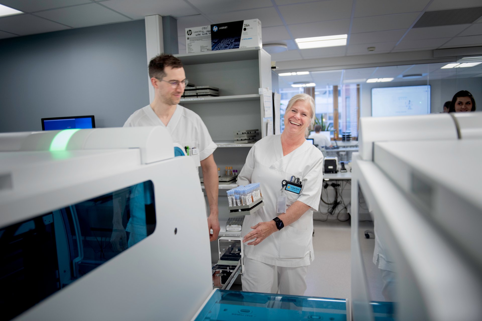 Two biomedical laboratory technicians in pleasant conversation at a hospital. Illustrates the importance of dialogue about pay and working conditions in the Spekter sector.