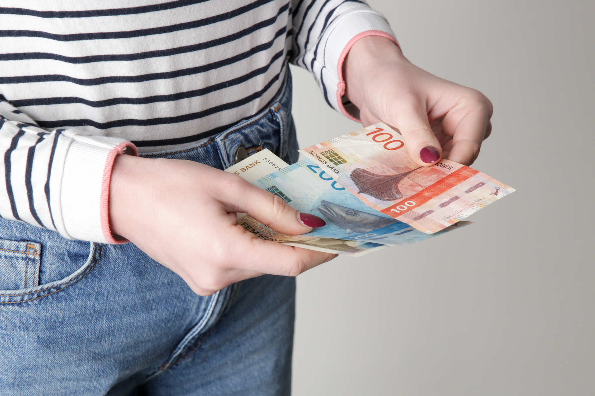 One person counts Norwegian banknotes, illustrates salary and the result of the wage settlement.