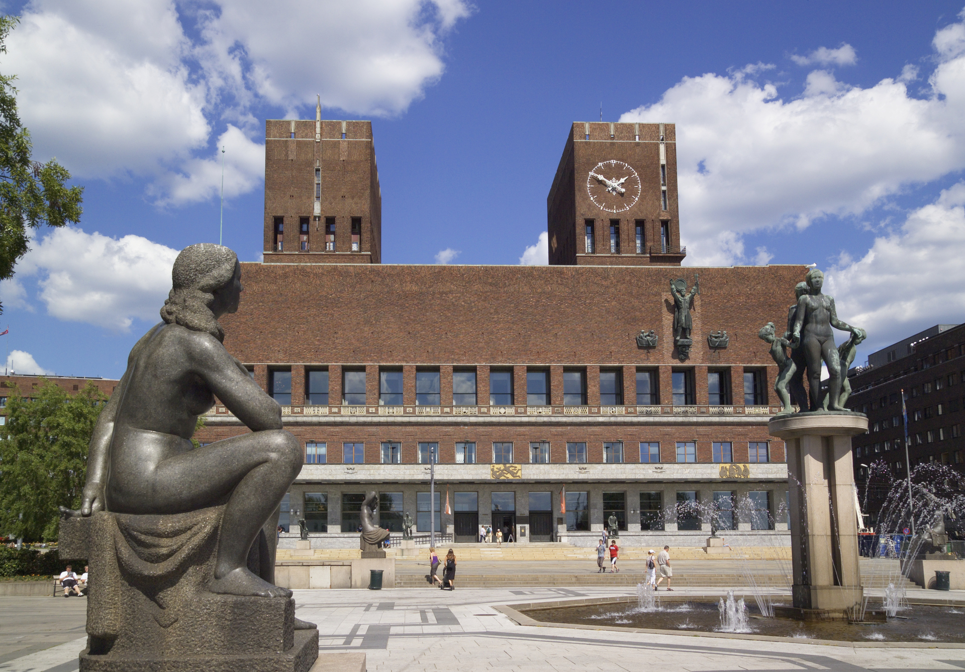 Oslo City Hall with sculptures and people outside, symbolizes public administration and negotiations on collective agreements in the municipal sector.
