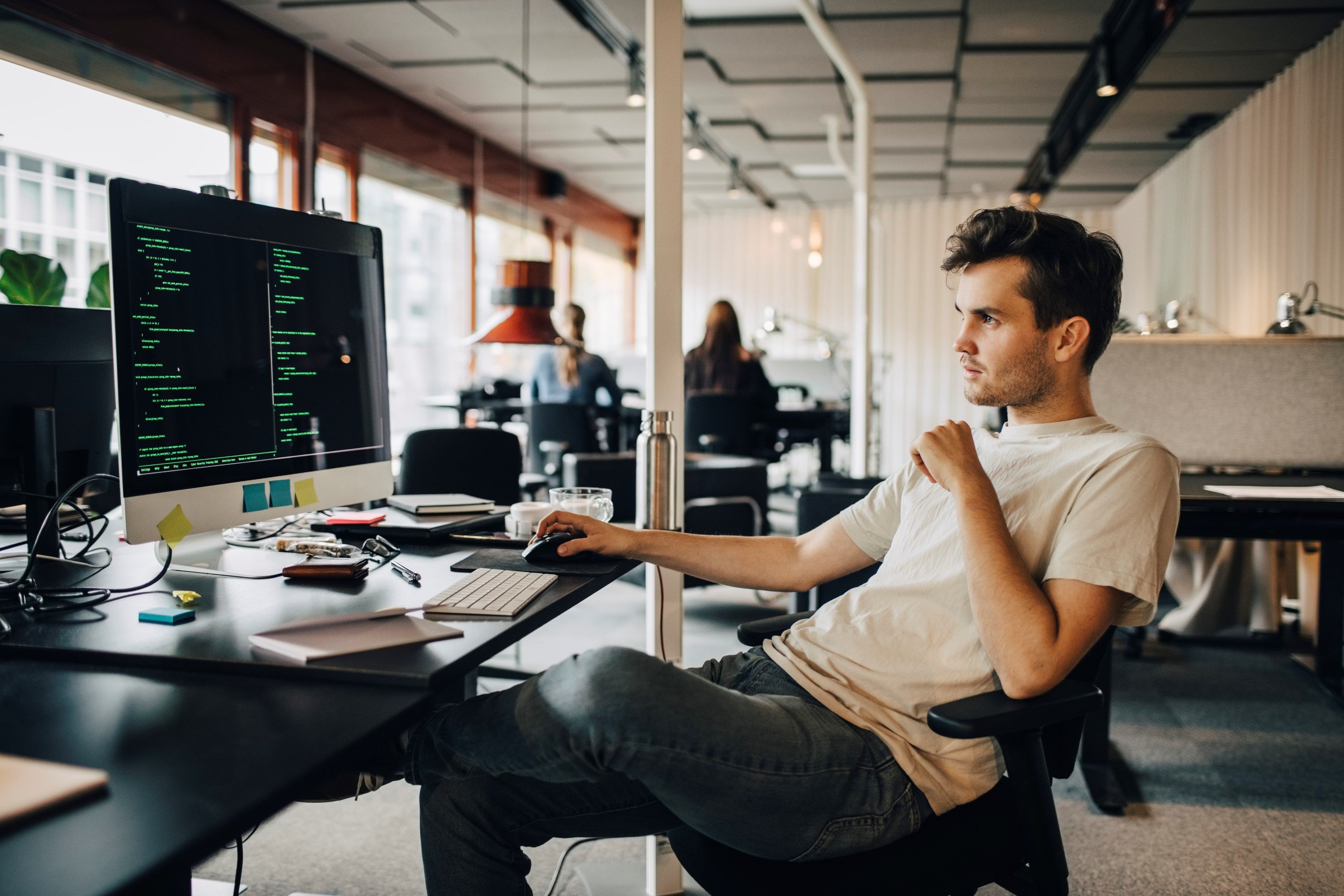A male employee works concentrated at a computer in a modern office. He represents those with particularly independent positions.
