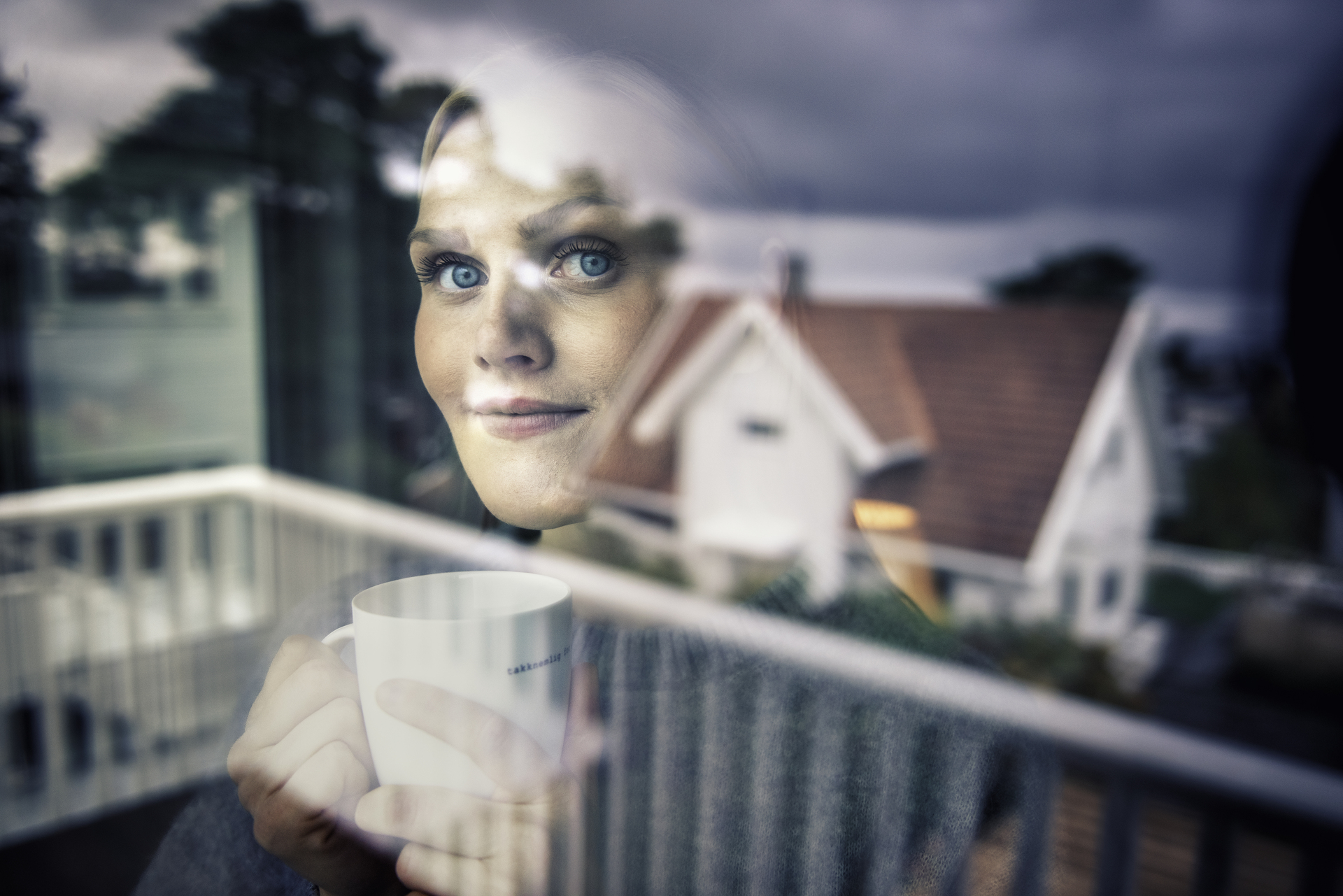 Lady looking out window, a house reflected in the window