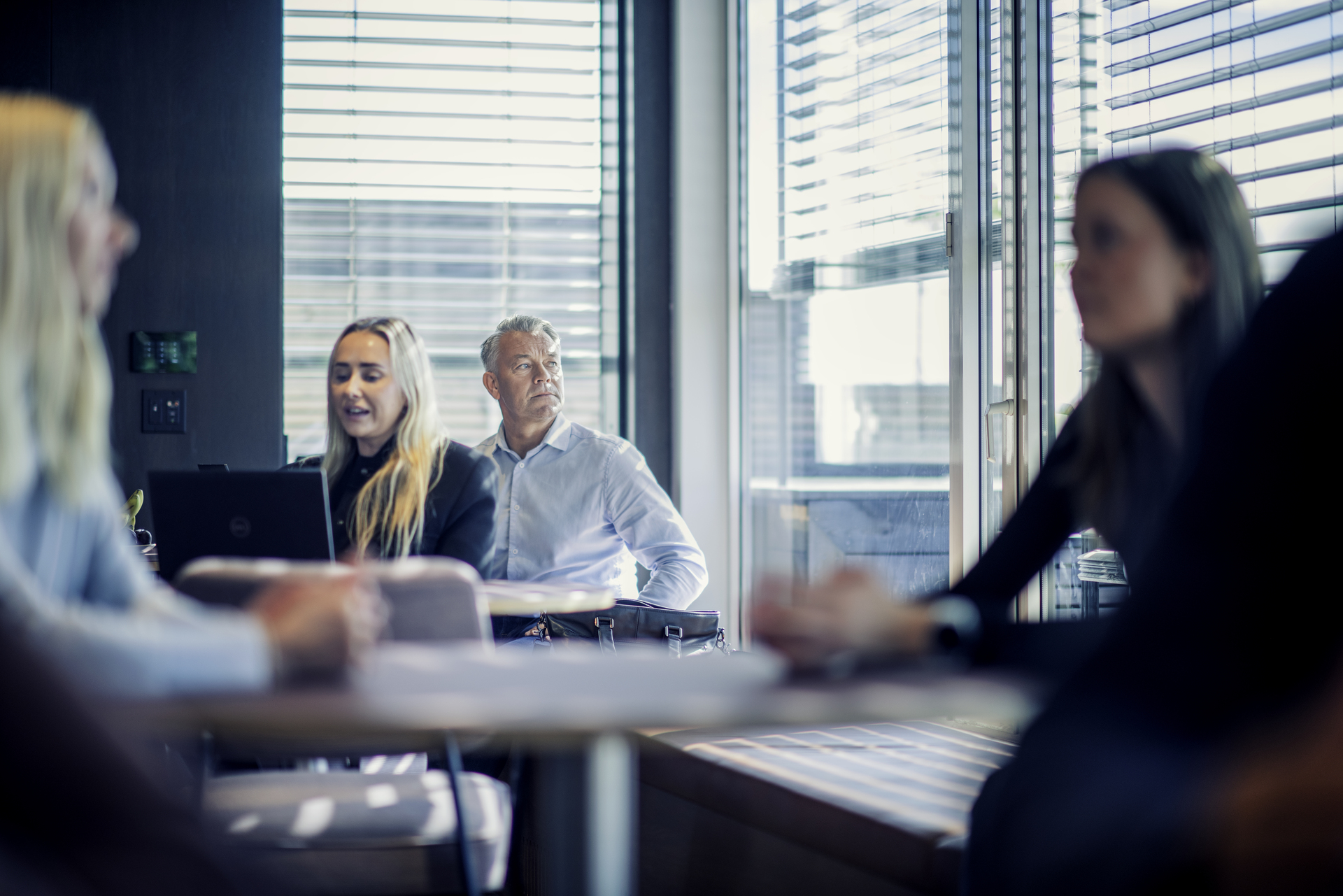Man in open-plan office looking out of the window with several people around him