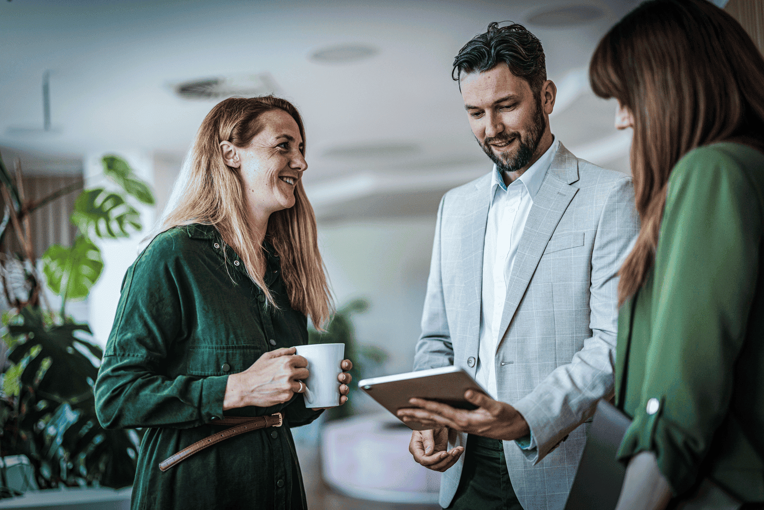 Three people chatting and looking at a tablet